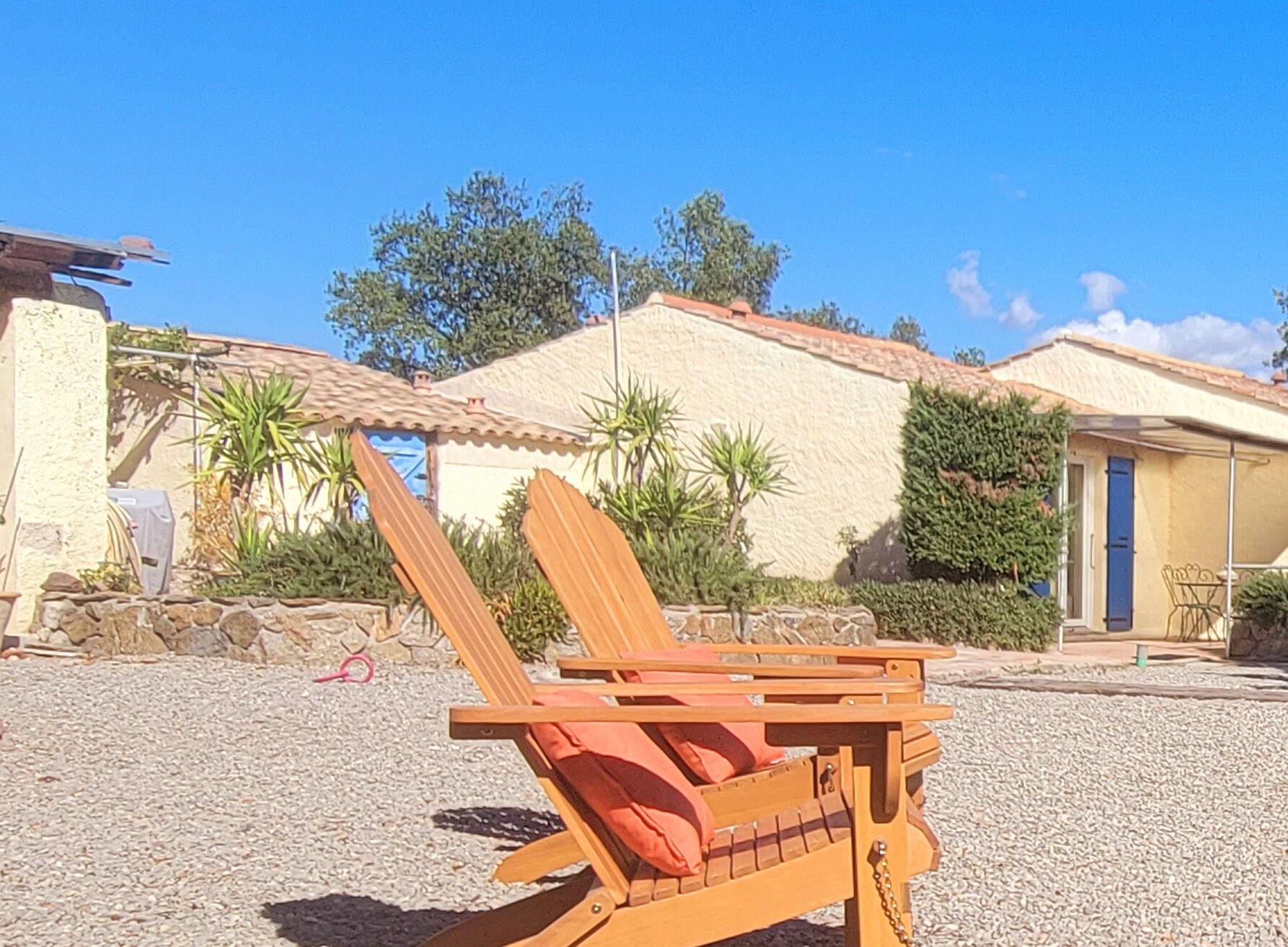 A beach chair with a cushion, a stone wall, and a building with a tiled roof.