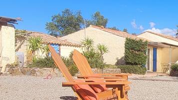 A beach chair with a cushion, a stone wall, and a building with a tiled roof.