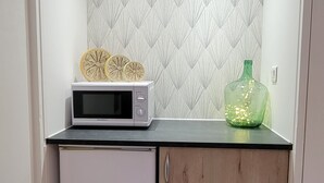A compact kitchen with a microwave, a small refrigerator, and a decorative wall with a geometric pattern. - le Mas du Rouquan (Vidauban)