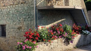 Un bâtiment en pierre doté d’un balcon et de jardinières.