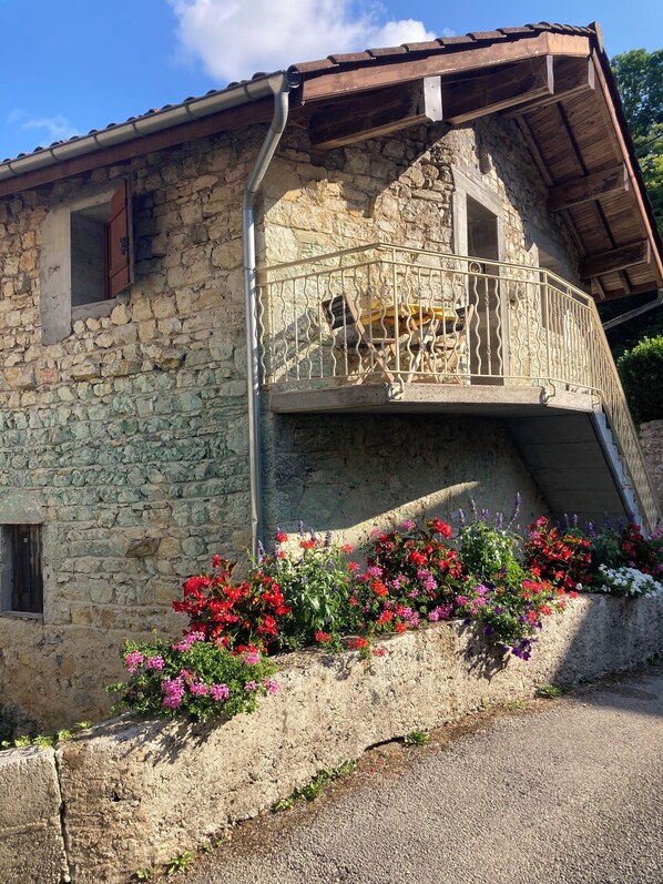 Un edificio de piedra con un balcón y macizos de flores.