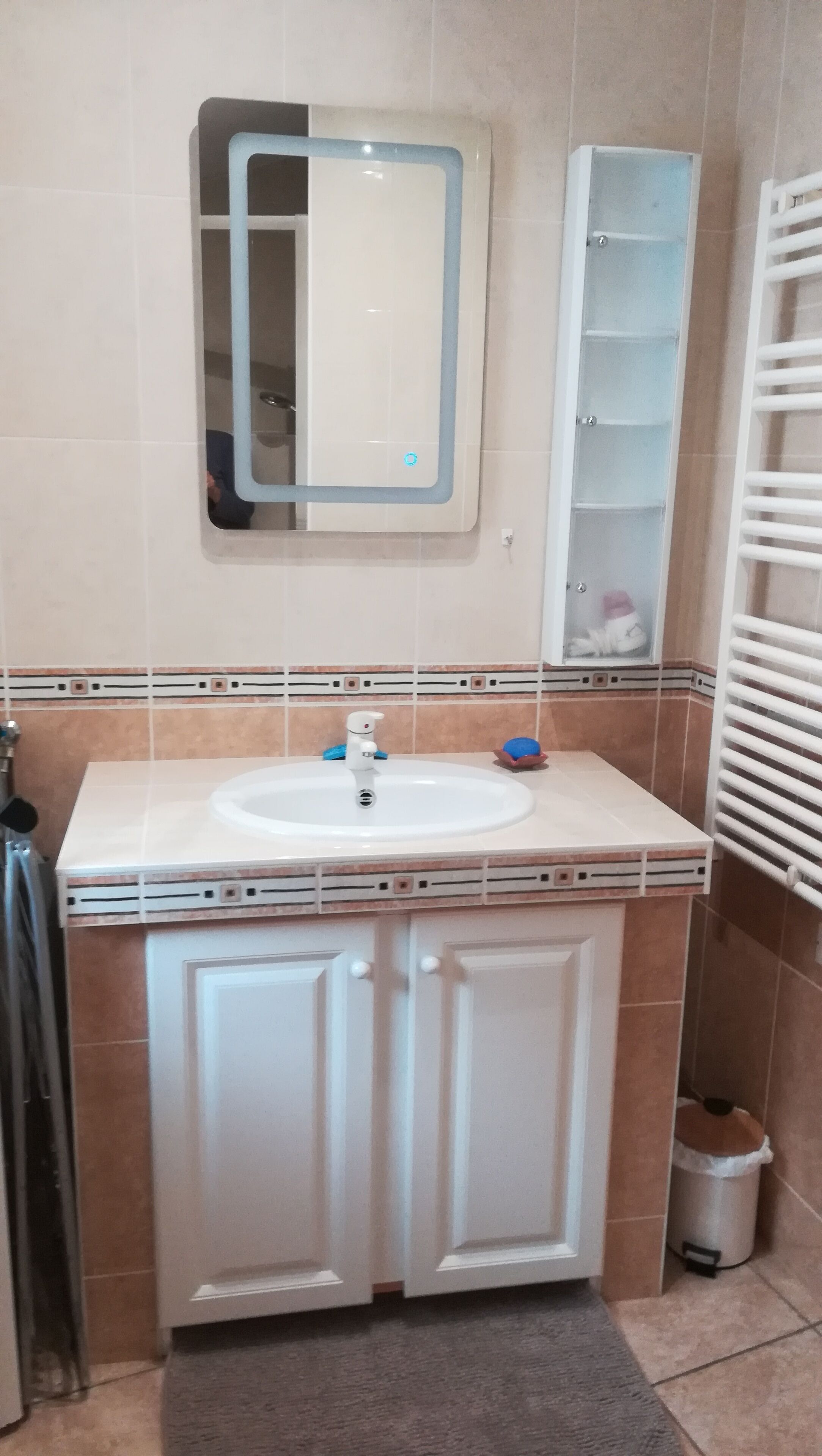 Un baño con un lavamanos blanco, un espejo y un armario.