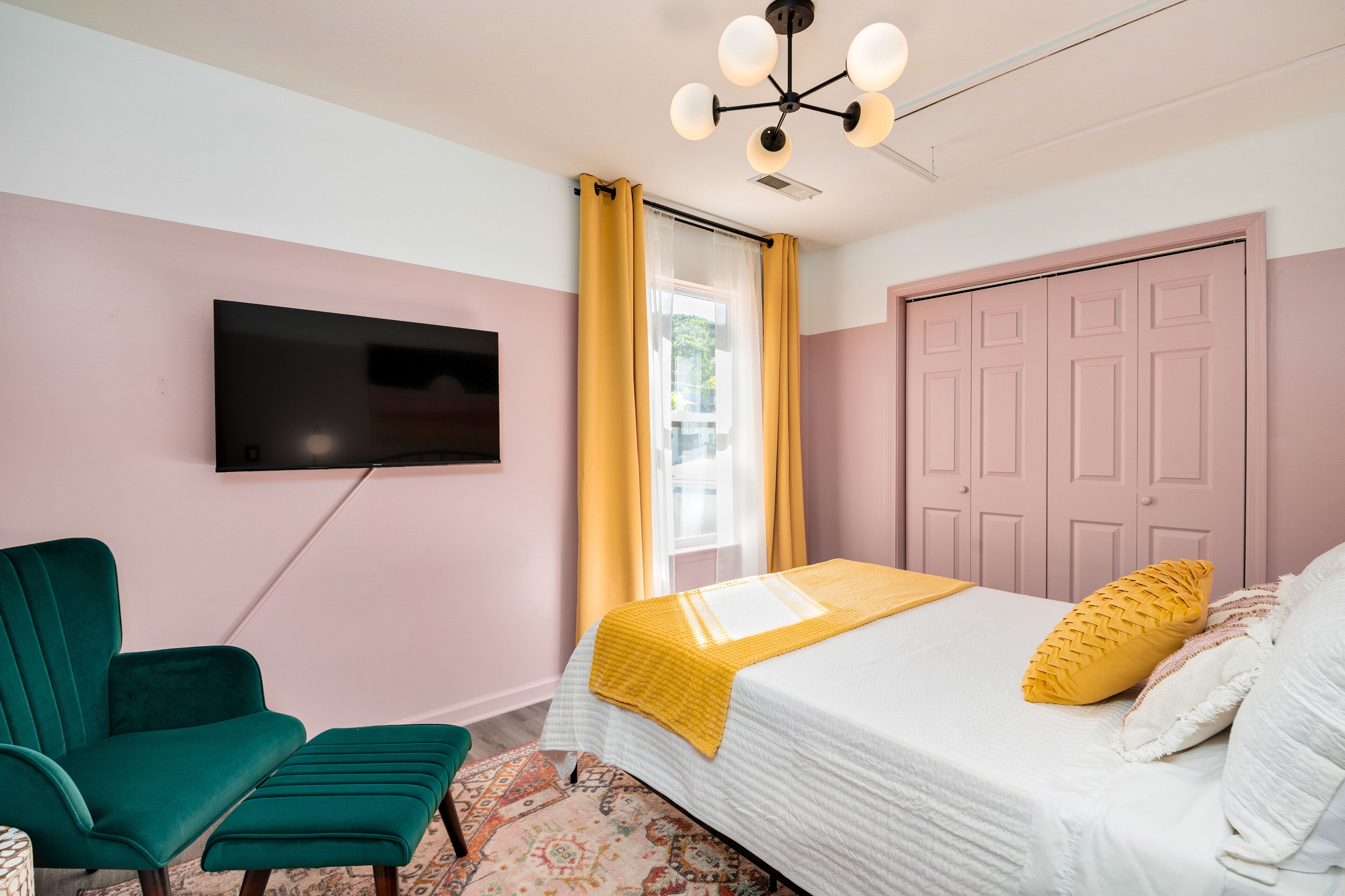 A bedroom with a bed, a television mounted on the wall, a chair, and a wardrobe.