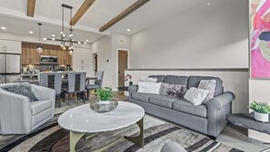 A modern living room with a grey sofa, white armchairs, and a round coffee table. - BRAND NEW|Hofburg by SSR|TopView|Luxury|PRIVATE HOT TUB|4BR plus Den ( BL# RES-11683 ) (Canmore)