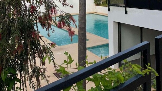 Ein modernes Hotel mit Pool, umgeben von Palmen und anderer Bepflanzung.