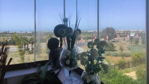Blick aus einem Fenster mit blauem Himmel, einem Blumentopf und einer entfernten Landschaft.