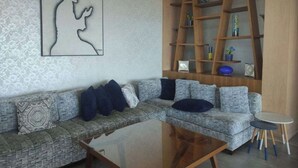 Ein modernes Wohnzimmer mit einer Eckcouch, einem Glastisch und einem Holzregal.
