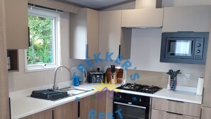 Een moderne keuken met houten kastjes, een ingebouwde magnetron, een gasfornuis en een raam dat voor natuurlijk licht zorgt.