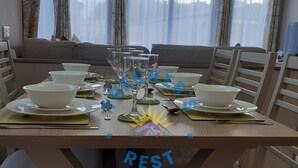 Een eettafel gedekt met kommen, borden en bestek, met een bord waarop 'REST' staat.