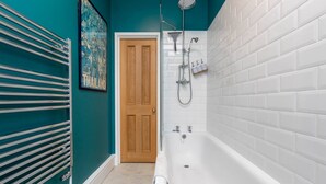 A bathroom with a bathtub, shower, and a towel rack. - Homely 1 Bedroom Apartment in Fulham! (London)