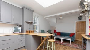 A compact kitchen with a wooden island, grey cabinets, and a small TV. - Homely 1 Bedroom Apartment in Fulham! (London)