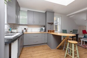 A modern kitchen with grey cabinets, a wooden countertop, and a built-in TV.