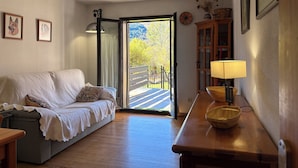 A cozy room with a sofa, a wooden table, a lamp, and a view through a glass door.