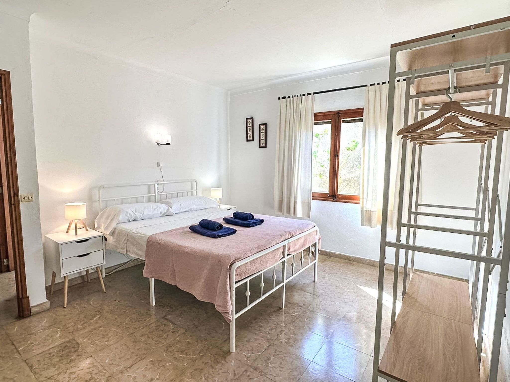 Een slaapkamer met een bed, nachtkastjes, een zwevende kledingkast en een raam met gordijnen.