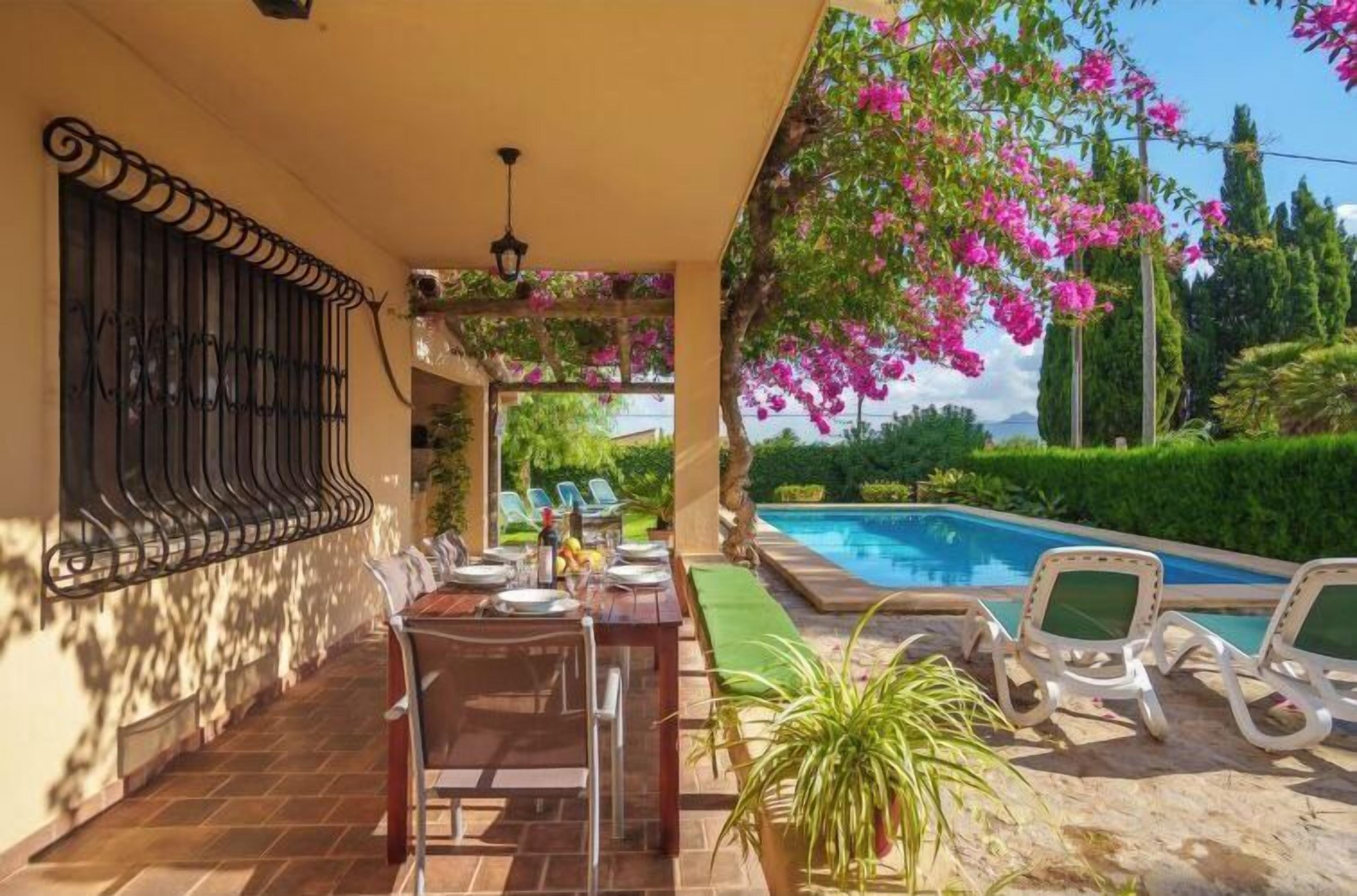 Eine Terrasse mit Esstisch, Stühlen und einem Poolbereich mit Liegestühlen.