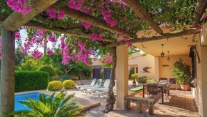 Un'area esterna coperta con piscina, lettini e tavolo da pranzo.