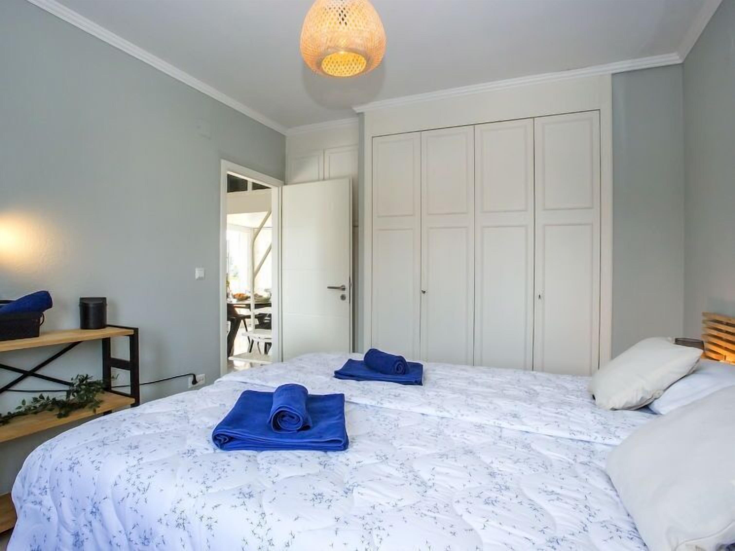 Une chambre avec deux lits, une armoire, un bureau et un luminaire suspendu.