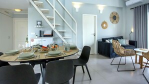 Una sala de estar moderna con comedor, una escalera y un sofá.