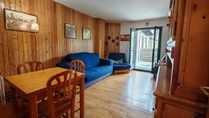 A wooden-paneled room with a dining table, chairs, a blue sofa, and a wooden cabinet.