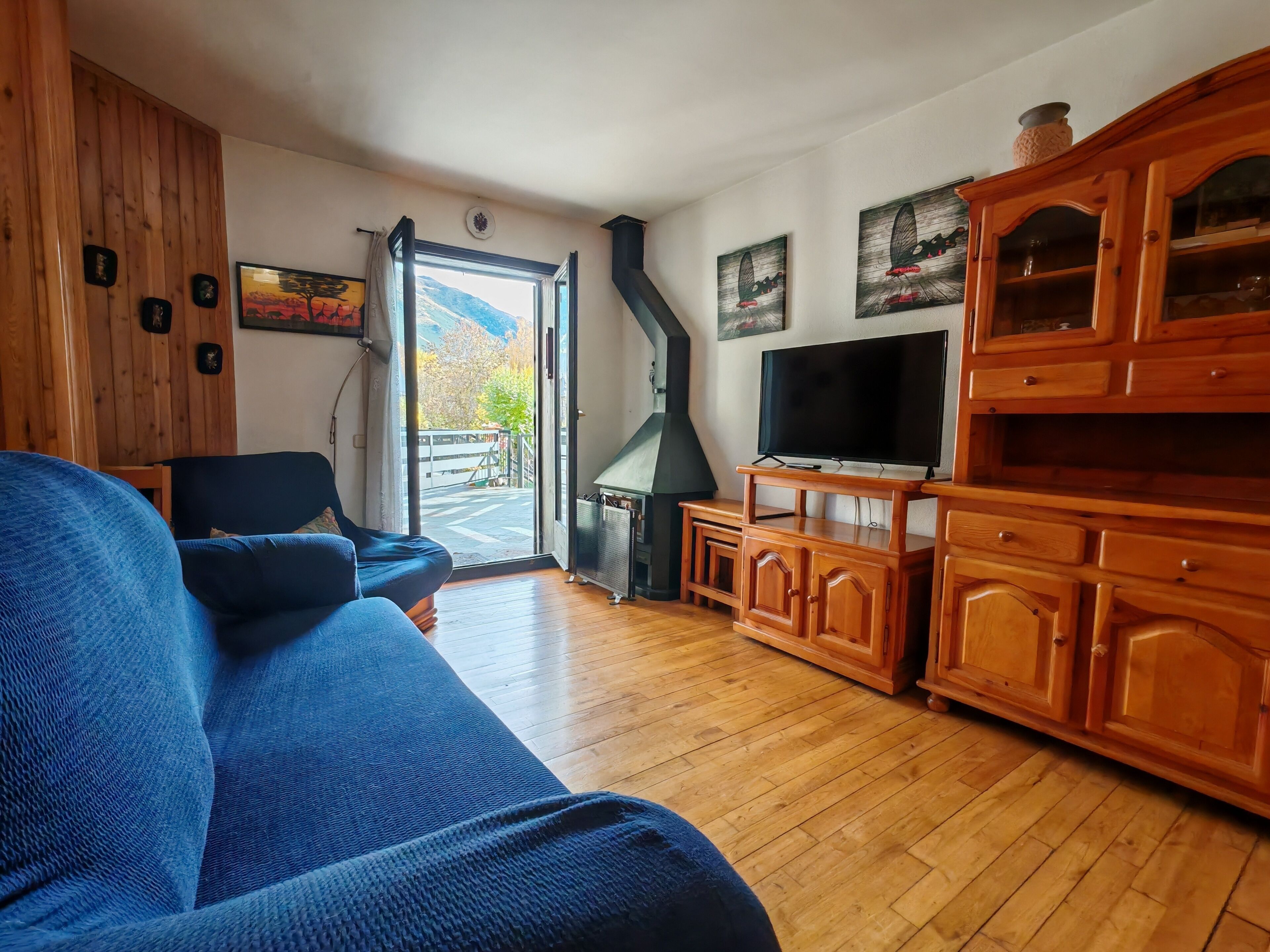 Een woonkamer met een bank, houten kasten, een televisie en een open haard.