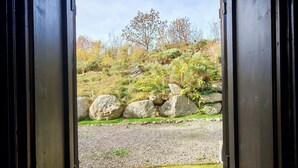 A doorway leading to a gravel path with a natural landscape view, including rocks and sparse vegetation.