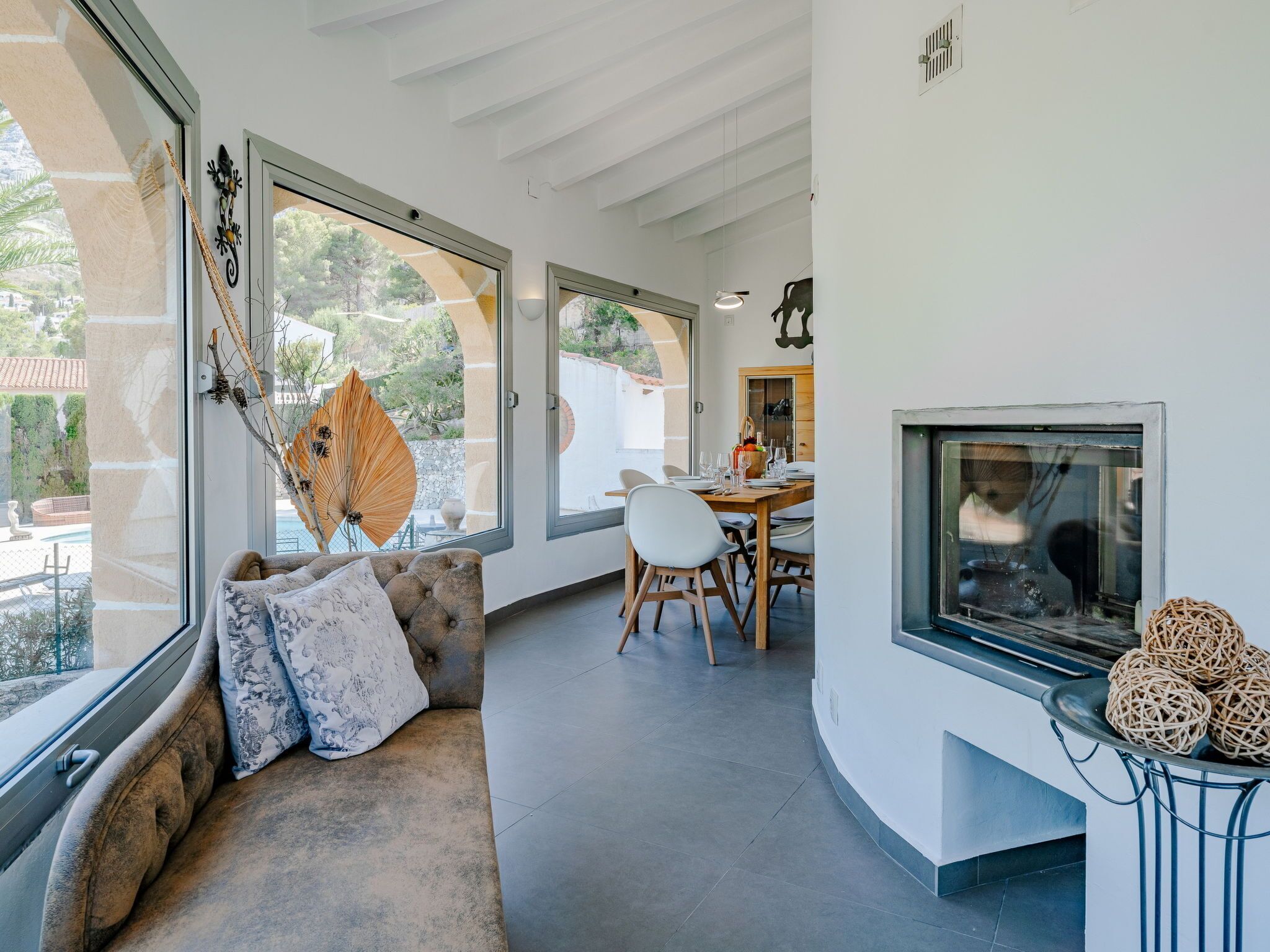 A modern living room with a large window, a fireplace, and a dining area.
