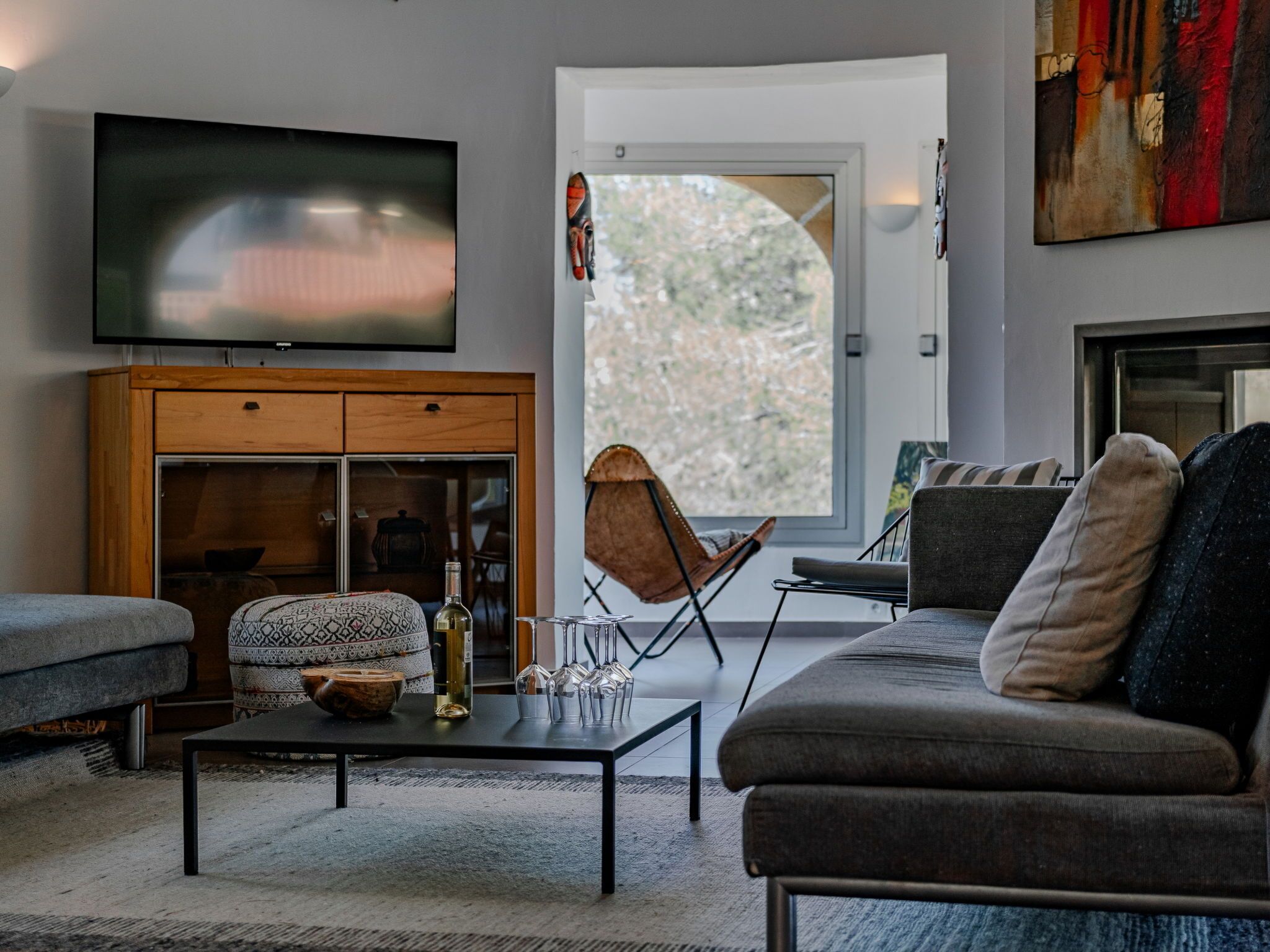 Una sala de estar moderna con un sofá, una mesa de centro, un televisor y vistas a través de un ventanal grande.