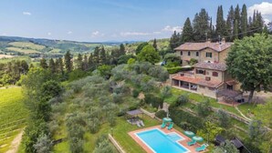 Une villa avec piscine, entourée d’une végétation luxuriante et de vignobles.