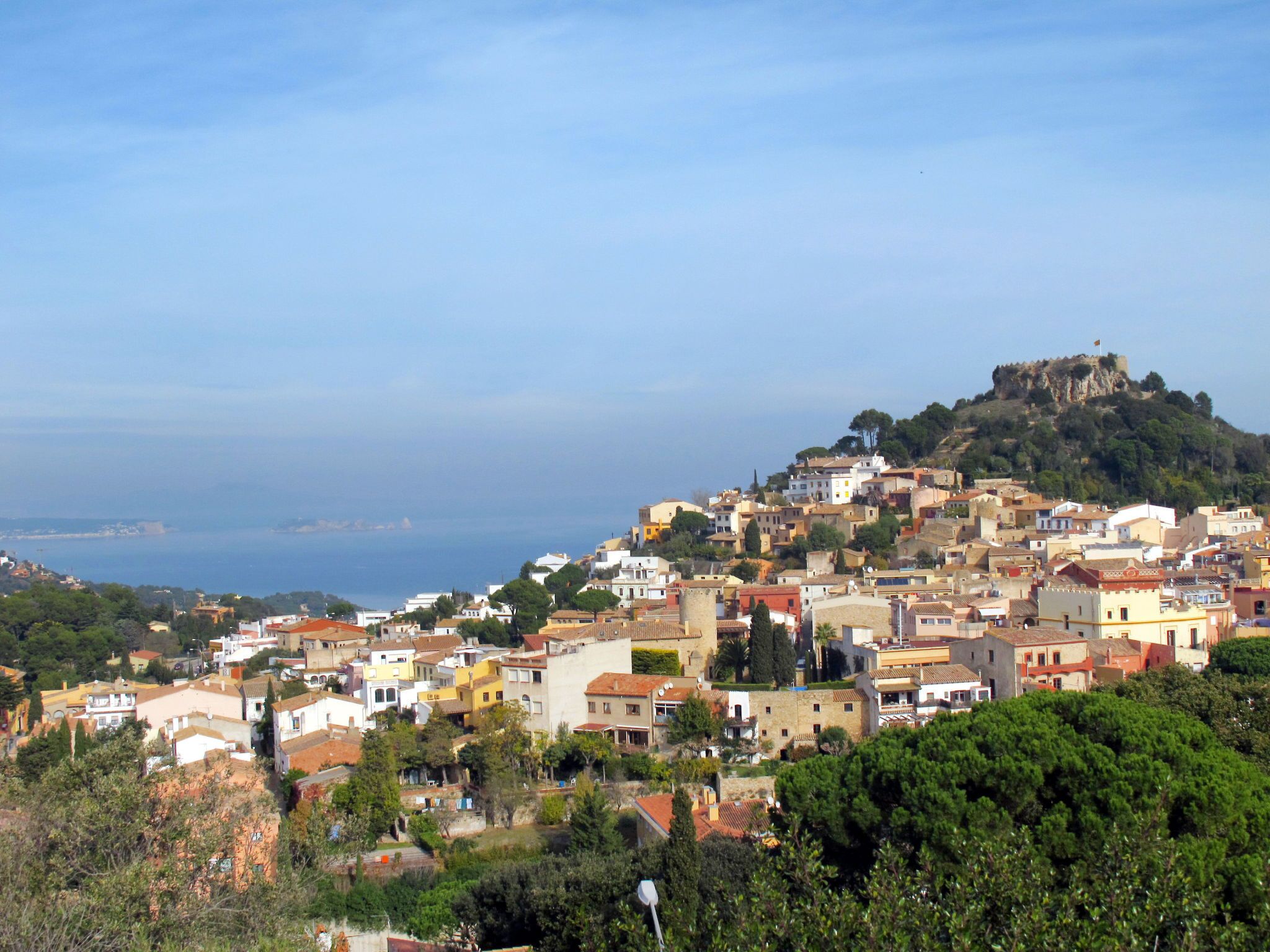 A coastal town with buildings on a hillside, overlooking the sea.