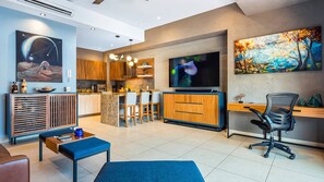 Una sala de estar moderna con televisión, asientos y una zona de cocina.