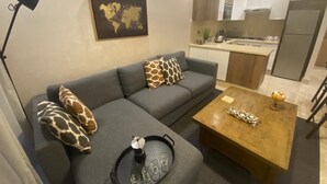 Ein modernes Wohnzimmer mit einem grauen Sofa, einem Holztisch und einer Weltkarte an der Wand.
