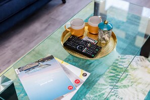 A glass table with a remote control, two mugs, and a decorative container. - Spacious 3 Bedroom Flat in the Heart of Shoreditch (London)