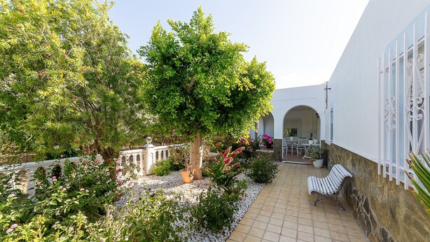 A courtyard with a tiled floor, a bench, a potted plant, and a white building with an arched entrance. - Holiday Home "Cortijo Indalo" with Pool & Wi-Fi (Pechina)