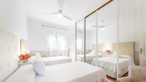 A hotel room with two beds, a large mirror, ceiling fans, and a small table with flowers. - Holiday Home "Cortijo Indalo" with Pool & Wi-Fi (Pechina)