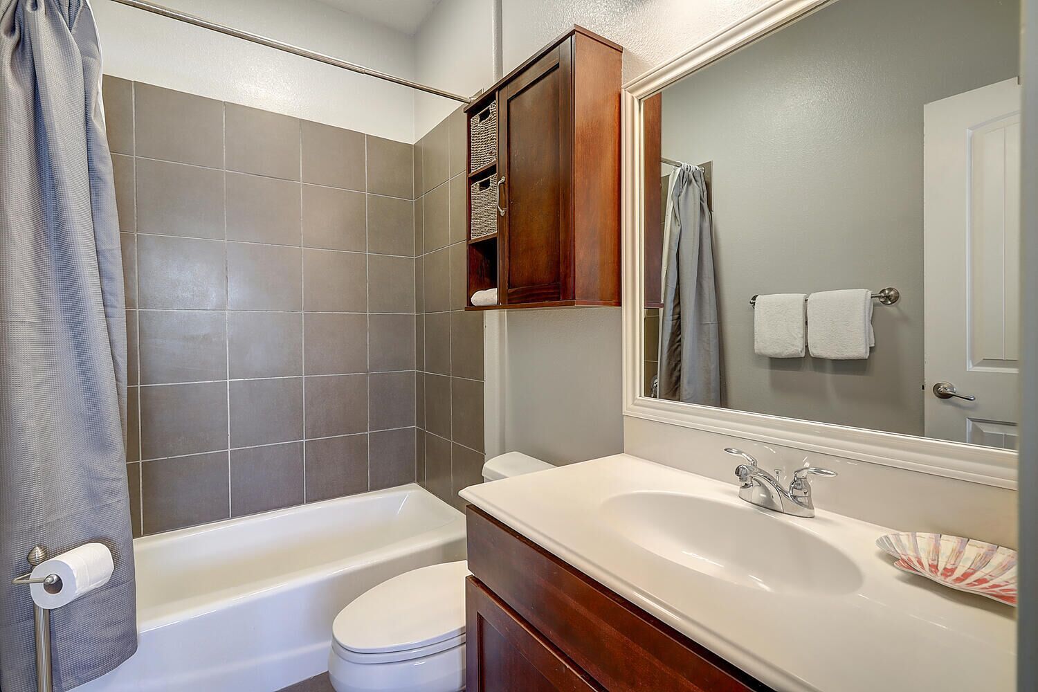Un bagno con vasca, wc, lavabo e specchio.