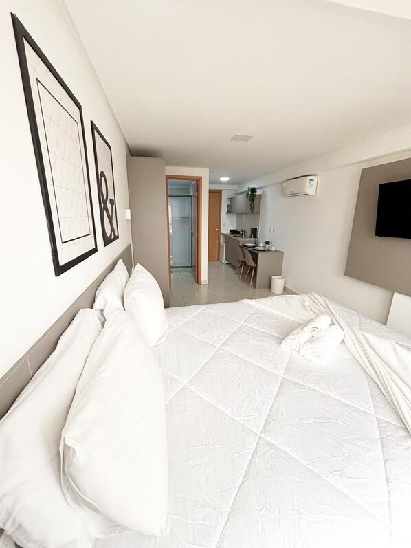 A hotel room with a large bed, a desk, and a television.
