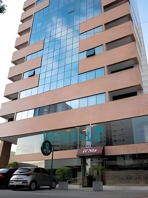 Un edificio de varios pisos con fachada de vidrio y un cartel que dice 'D'NETO' a nivel de calle.