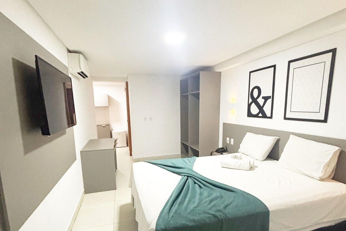 Habitación de hotel con cama, mesita de noche y televisor montado en la pared.