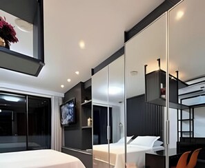 Quarto de hotel moderno com uma cama grande, televisão e varanda.