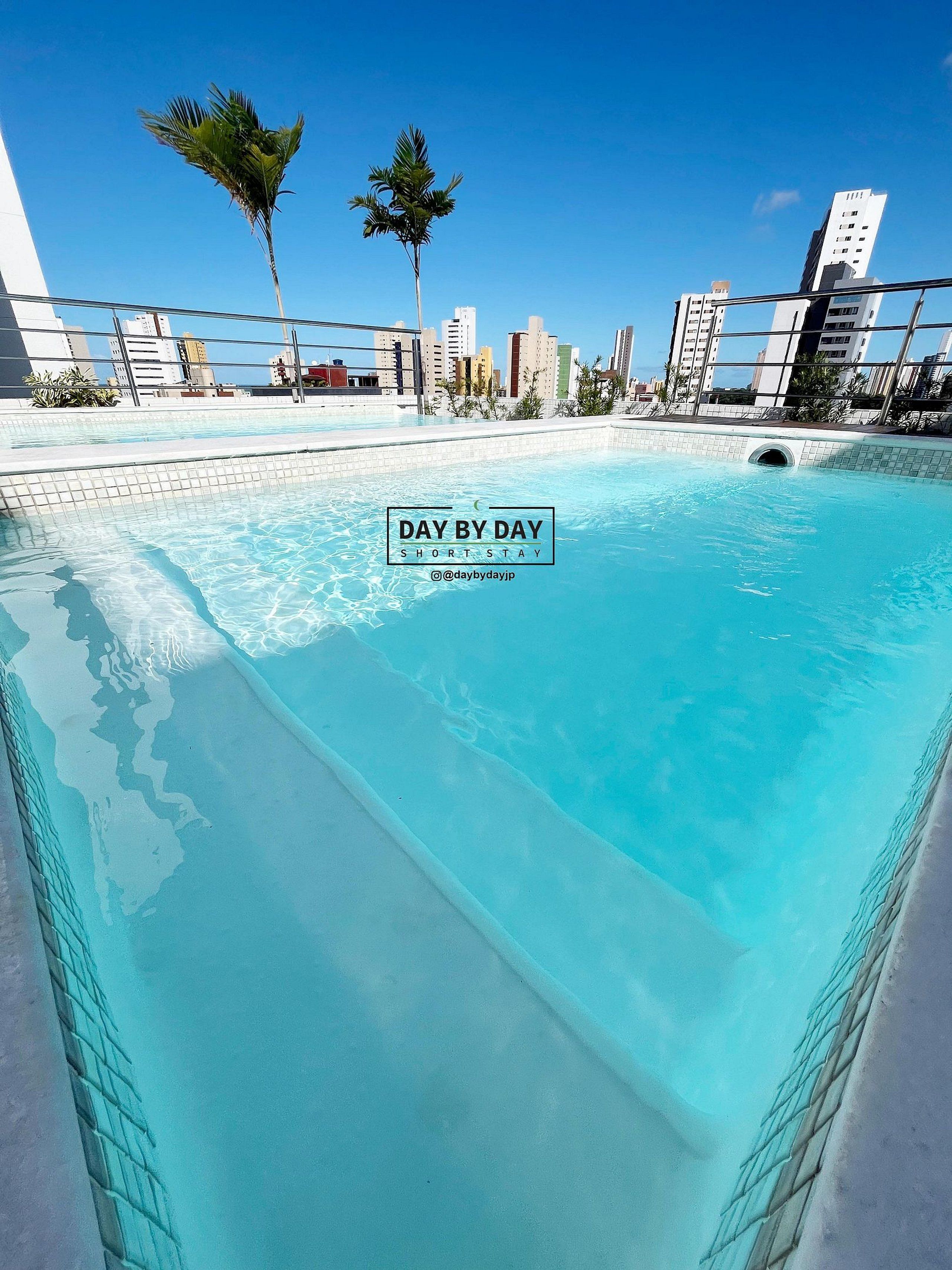 A clear blue pool with a city skyline in the background.
