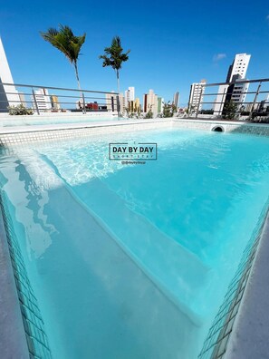 Una piscina azul cristalina con el horizonte de una ciudad al fondo.