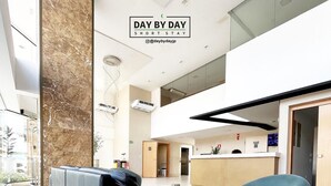A modern interior with a black leather sofa, a blue bean bag, and a kitchen area. - Manaira Apart Hotel (João Pessoa)