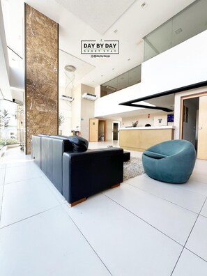 Un interior moderno con un sofá de cuero negro, un sillón orejero azul y una zona de cocina.
