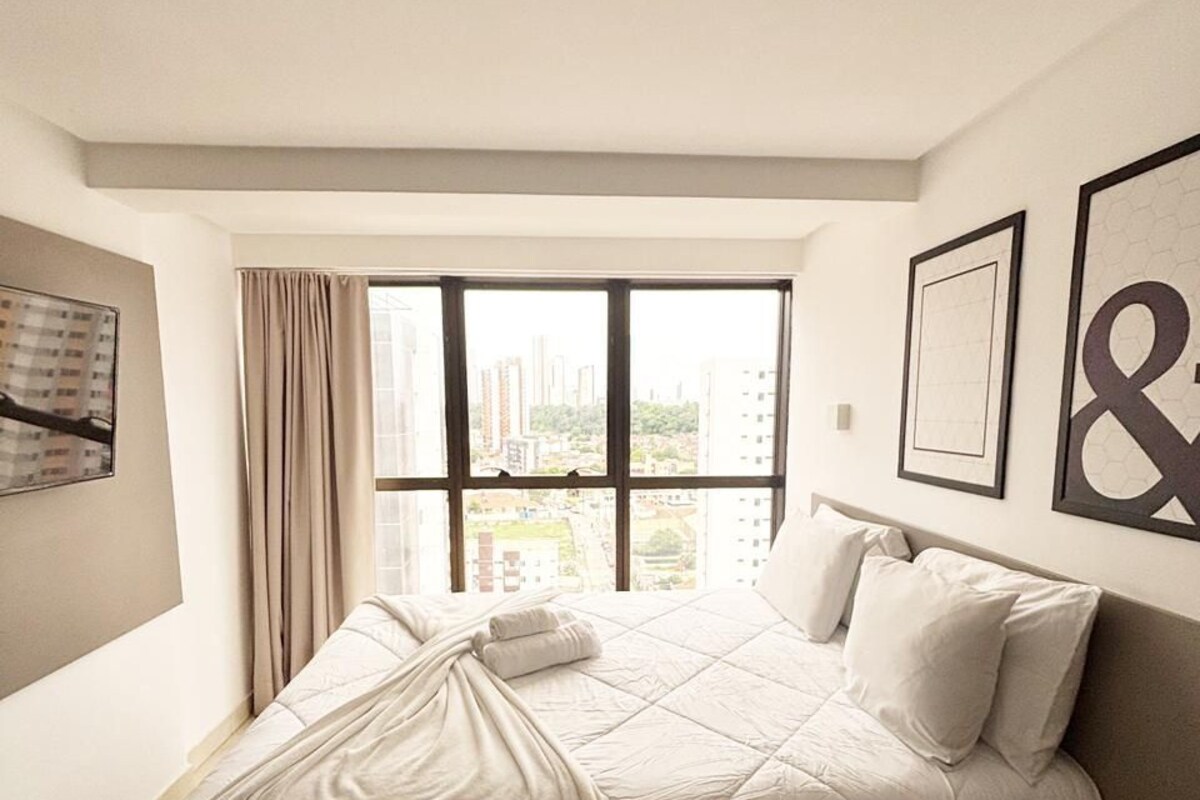 Un dormitorio con un ventanal grande, una cama y vistas a la ciudad.