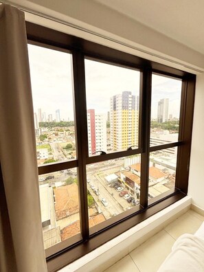 A room with a large window offering a view of a cityscape, including high-rise buildings and a road.