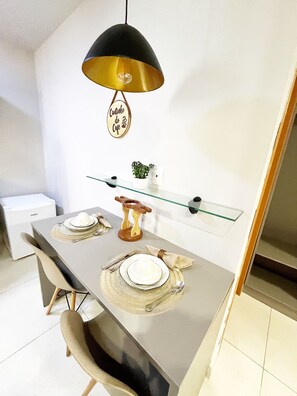 A modern dining area with a glass-top table, metal chairs, and a pendant light.