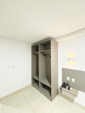 A room with a built-in wardrobe, a wall-mounted telephone, and a light fixture. - Manaira Apart Hotel (João Pessoa)