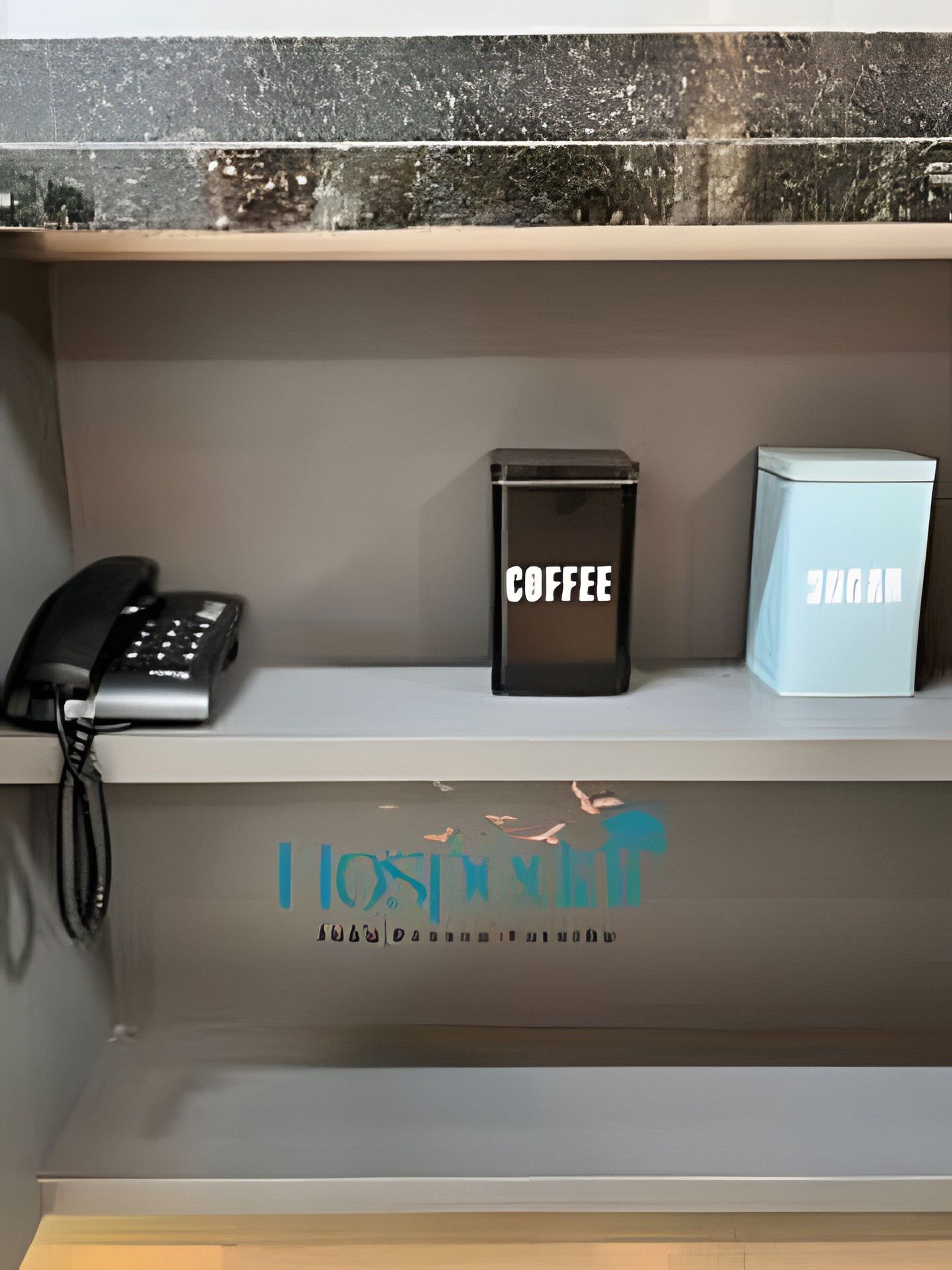 Un comptoir de réception d’hôtel équipé d’un téléphone, d’une machine à café et d’un mini-bar.