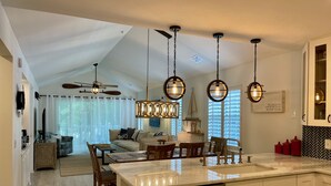 A modern kitchen with a central island, pendant lights, and a ceiling fan.