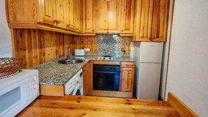 Eine kompakte Küche mit Holzausstattung, einer eingebauten Mikrowelle, einem Geschirrspüler und einem Kühlschrank.